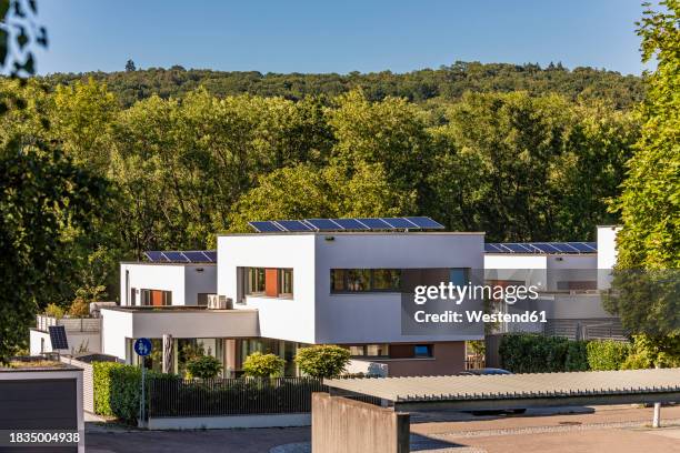 germany, baden-wurttemberg, esslingen, modern suburban houses with forested hill in background - einfamilienhaus mit solarzellen stock-fotos und bilder