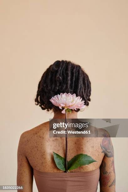 young woman with flower in tube top against brown background - body acne photos et images de collection