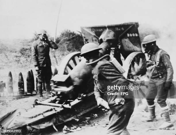 Gas mask wearing gunners of Battery A, 130th Field Artillery Regiment, 35th Infantry Division of the American Expeditionary Forces operate a Canon de...