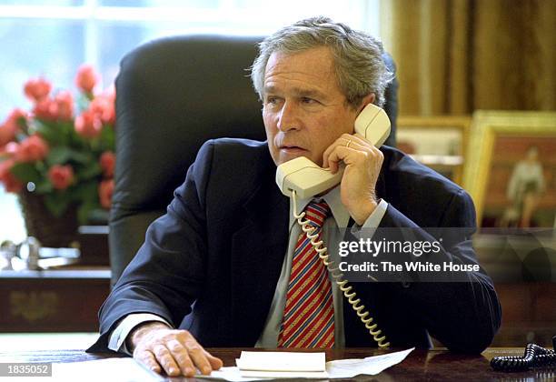 President George W. Bush uses a telephone to speak with British Prime Minister Tony Blair while in the Oval Office at the White House March 7, 2003...
