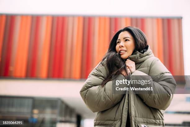 beautiful businesswoman wearing padded jacket outside office building - puffer jacket stock pictures, royalty-free photos & images