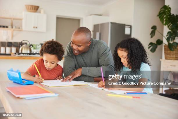 dad helping his two children with their homework at a kitchen table - homework kitchen table stock pictures, royalty-free photos & images