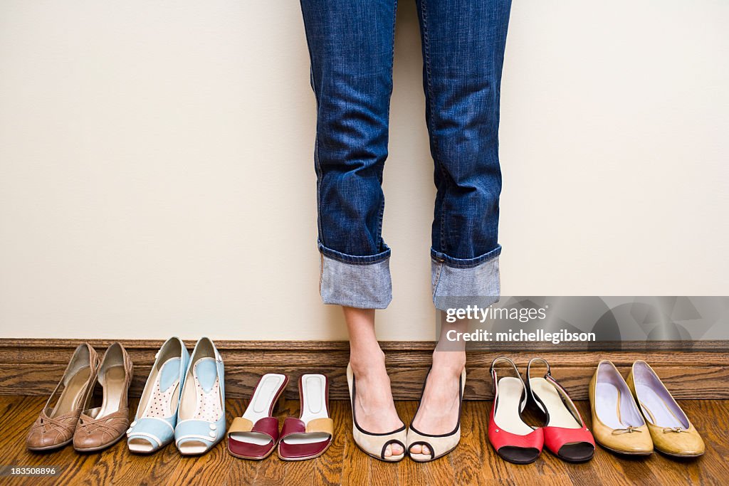 Woman stands wearing heels with her collection of Shoes
