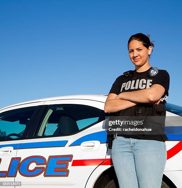 hispanic police woman standing against car - police woman stock pictures, royalty-free photos & images