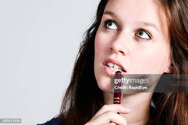 pretty redhead looks to side. thinking, pen at mouth - mouth thinking stockfoto's en -beelden