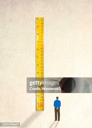 Man looking at oversized ruler Man looking at oversized ruler