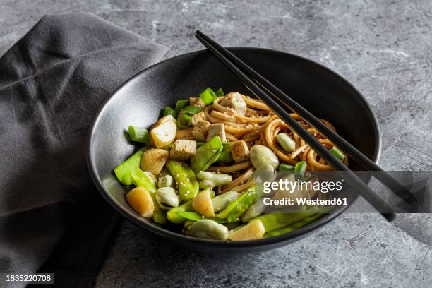 bowl of vegan miso udon bowl with tofu, snap peas, broad beans and turnips - udon noodle stock pictures, royalty-free photos & images