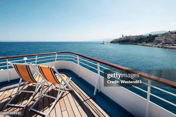 france, haute-corse, deck chairs on bow of ferry sailing toward coast of corsica island - proa fotografías e imágenes de stock
