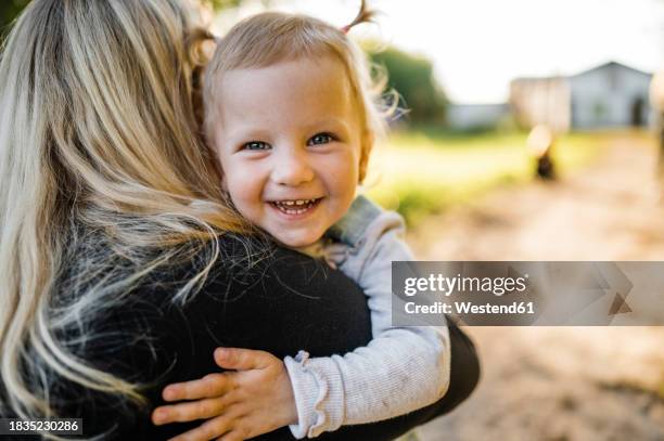 mother carrying happy daughter in park - happy toddlers stock pictures, royalty-free photos & images