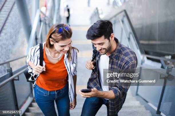 lovely couple standing at railway station and using smartphone with gps navigation - passenger train stockfoto's en -beelden