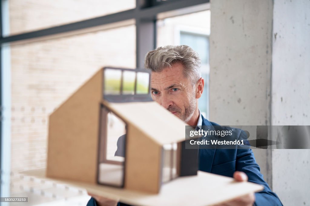 Mature businessman examining model house in office