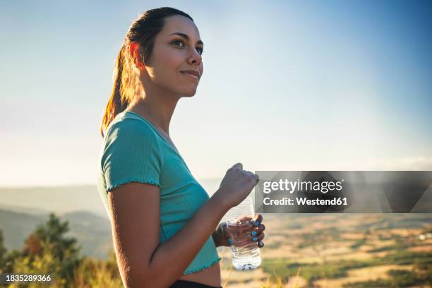 beautiful woman holding water bottle on sunny day - smirking stock pictures, royalty-free photos & images