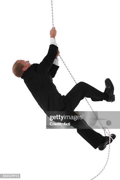 businessman climbing rope - hanging rope object stock pictures, royalty-free photos & images