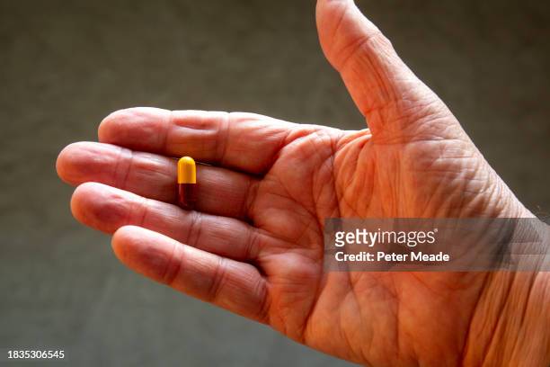an aging male hand holding an amoxicillin capsule - amoxicillin 個照片及圖片檔