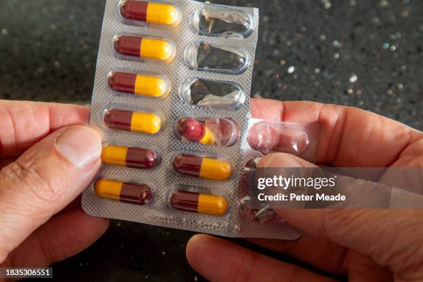 a patient's hands removing an amoxicillin capsule from a blister - amoxicillin stock-fotos und bilder