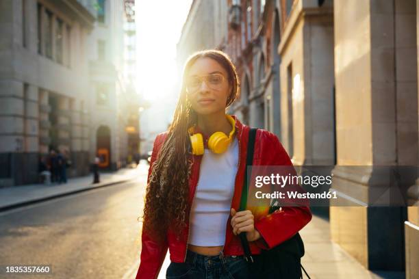 young woman wearing eyeglasses and walking with backpack in city - variable schärfentiefe stadt stock-fotos und bilder