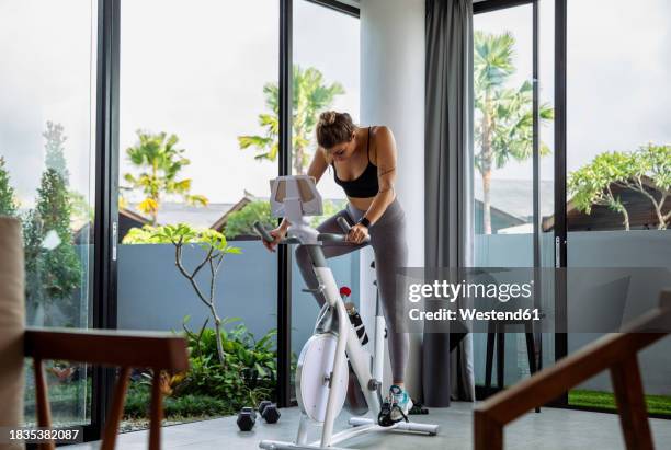 woman exercising on exercise bike at home - cyclette foto e immagini stock
