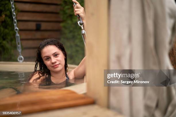 happy woman relaxing in bath holding on to chain - woman bath tub wet hair stock pictures, royalty-free photos & images