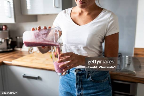 woman pouring healthy milkshake in glass at home - milkshake stock pictures, royalty-free photos & images