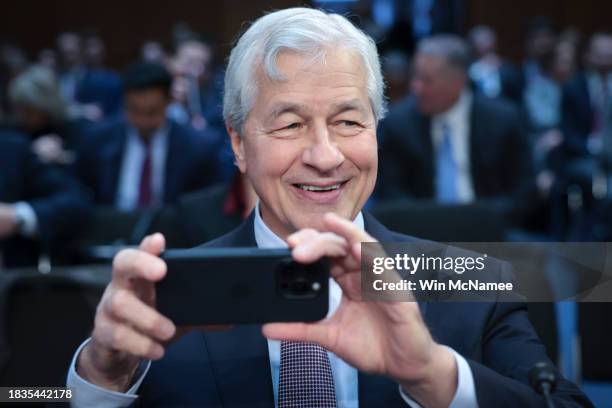 Jamie Dimon, Chairman and CEO of JPMorgan Chase, takes a picture of news photographers as he arrives to testify at a Senate Banking Committee hearing...