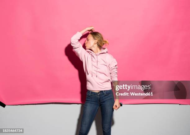 woman puckering and flexing muscle against pink background - starke frau stock-fotos und bilder