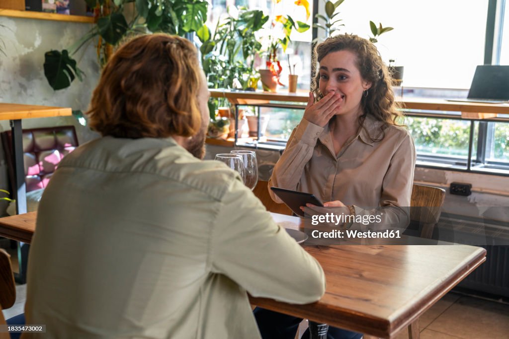 Surprised woman with boyfriend sitting at table in cafe