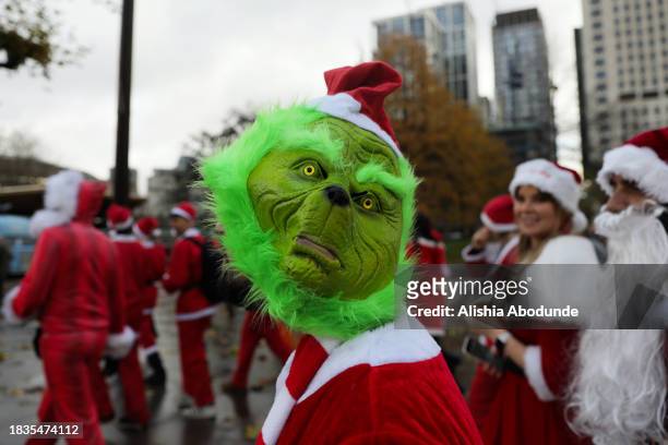 Revellers dressed as The Grinch and Santa Claus take part in the annual SantaCon event on December 9, 2023 in London, England. A flurry of Santas and...