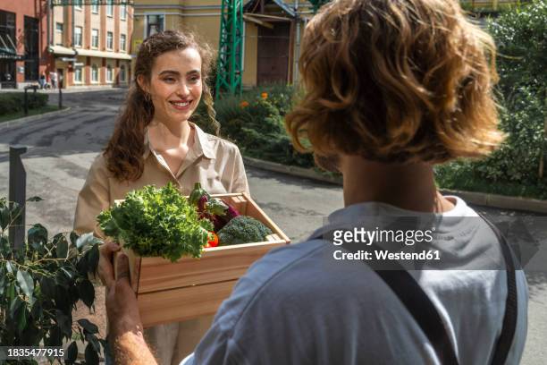 smiling customer receiving vegetable crate from owner - crisp stock pictures, royalty-free photos & images