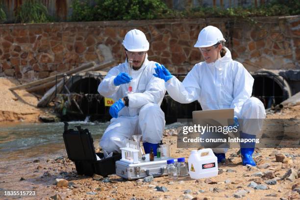 cientistas ou biólogos usam roupas de proteção, coletam drenos de água de fábricas para analisar águas residuais - águas residuais - fotografias e filmes do acervo