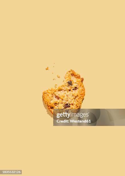 raisin cookie with missing bite against yellow background - raisin cookie stock illustrations