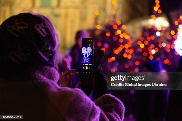 Woman takes a photo during the Christmas tree opening ceremony at the Sophia Square on December 6, 2023 in Kyiv, Ukraine. Due to the fact that...