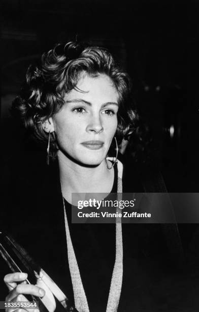 American actress Julia Roberts, wearing a dark crew neck top with hoop earrings, attends the NATO/ShoWest '91 convention, held at Bally's Hotel &...