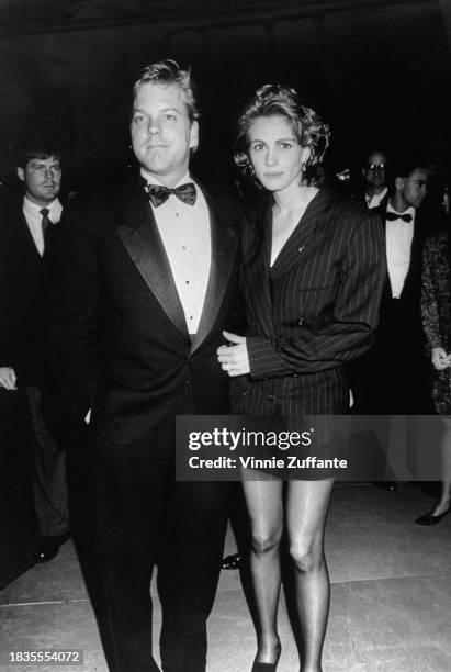 Canadian actor Kiefer Sutherland, wearing a tuxedo and bow tie, and American actress Julia Roberts, who wears a double-breasted pinstripe jacket and...