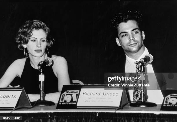 American actress Julia Roberts, wearing a crew neck, sleeveless top with hoop earrings, and American actor Richard Grieco attend a press conference...