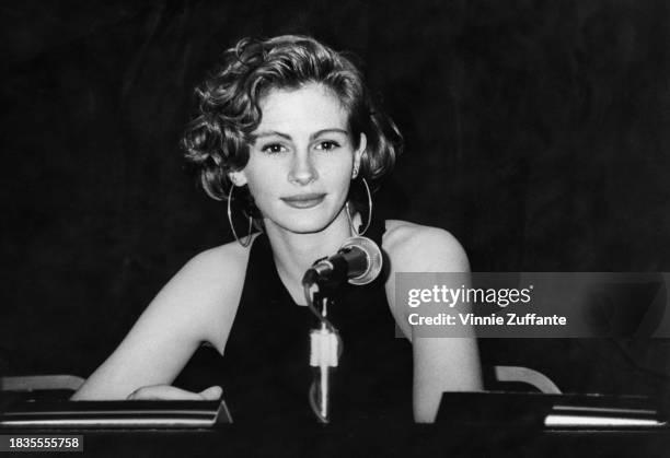 American actress Julia Roberts, wearing a crew neck, sleeveless top with hoop earrings, attends a press conference at the NATO/ShoWest '91...