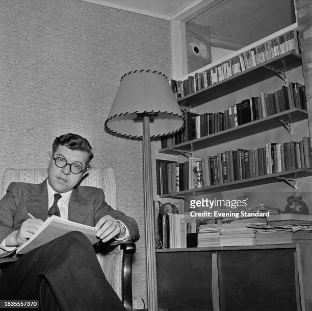 Science fiction author and Plumian Professor of Astronomy and Experimental Philosophy at Cambridge University, Fred Hoyle writes while seated next to...