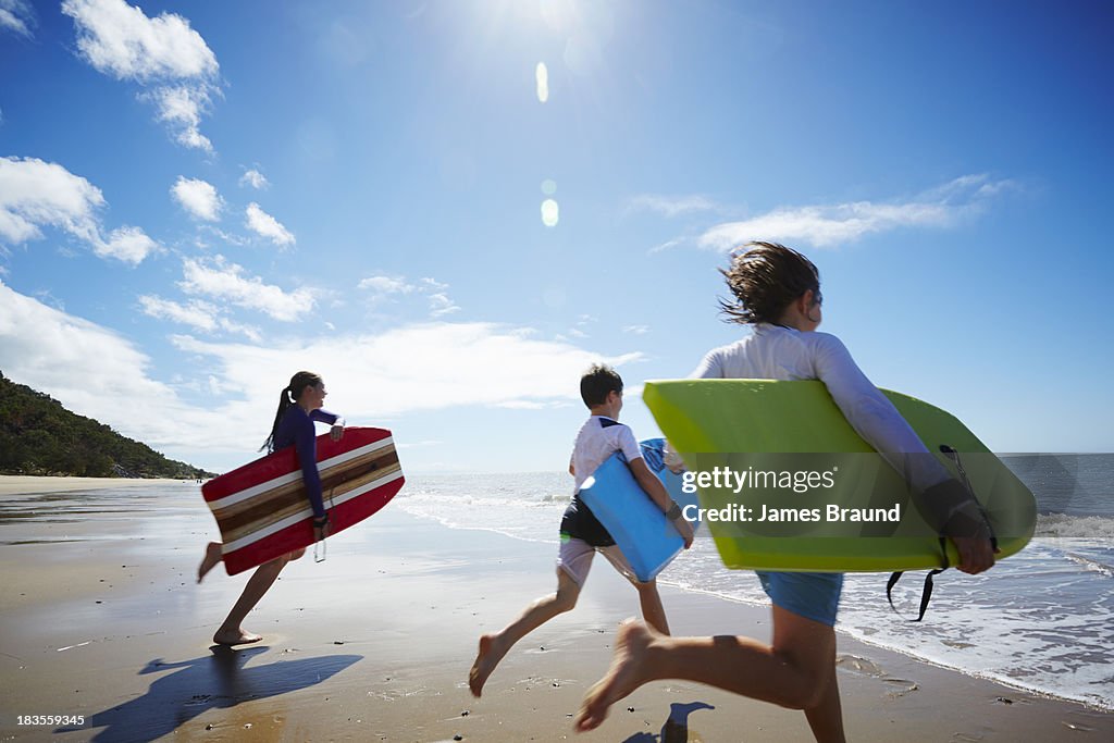 Three children running into the ocean