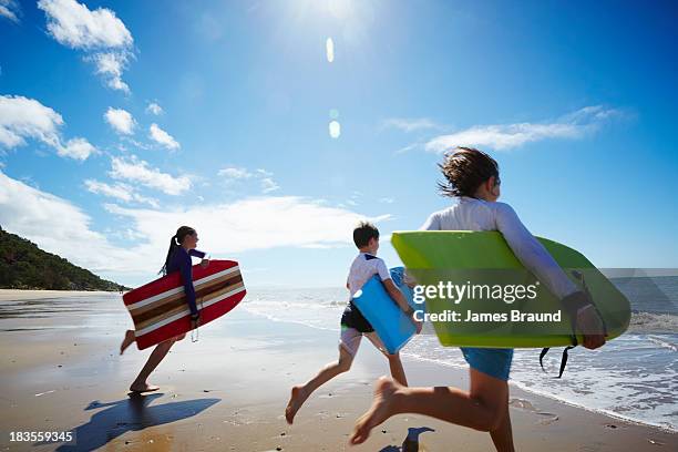 three children running into the ocean - beach boogie board fotografías e imágenes de stock