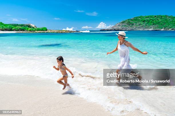 cute little girl with mother running on idyllic beach - caribbean sea stock pictures, royalty-free photos & images