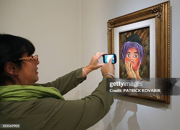 Woman takes a picture of the painting "La máscara" by Mexican painter Frida Kahlo during the exhibition "Frida Kahlo / Diego Rivera Art in fusion" at...