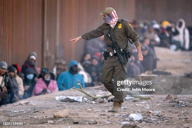 Border Patrol agent instructs immigrants to sit while awaiting transport from the U.S.-Mexico border on December 06, 2023 in Lukeville, Arizona. A...