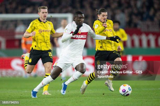 Serhou Guirassy of Stuttgart is tackled by Marcel Sabitzer of Dortmund during the DFB cup round of 16 match between VfB Stuttgart and Borussia...
