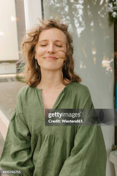 smiling blond woman enjoying wind outside shop - olhos fechados imagens e fotografias de stock