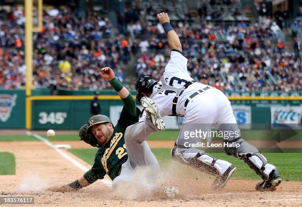 Stephen Vogt of the Oakland Athletics slides into home plate to score a run in the fourth inning against Alex Avila of the Detroit Tigers during Game...