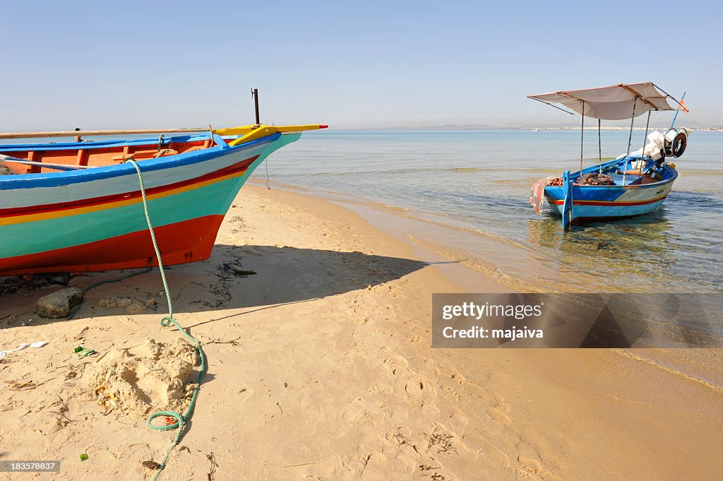 Small colorful fishing boats on shore and beach sand