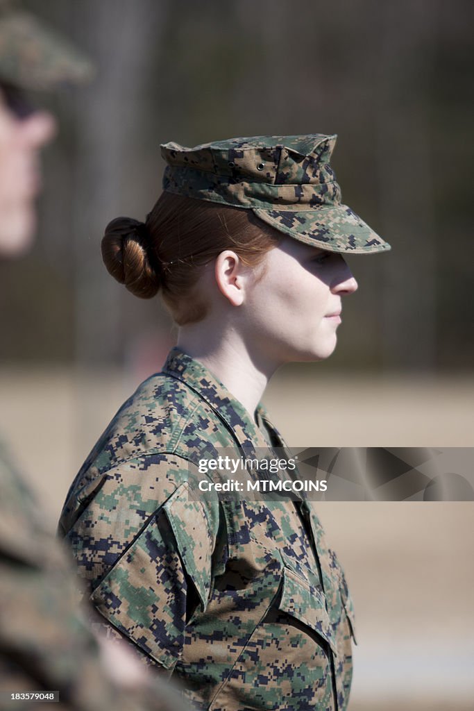 A woman Maine in uniform standing at attention