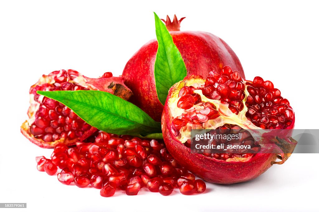 Whole and cracked pomegranate with leaves and seeds