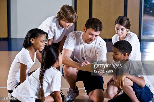 vielfältige gruppe von kindern im fitnessraum mit trainer - sportunterricht stock-fotos und bilder