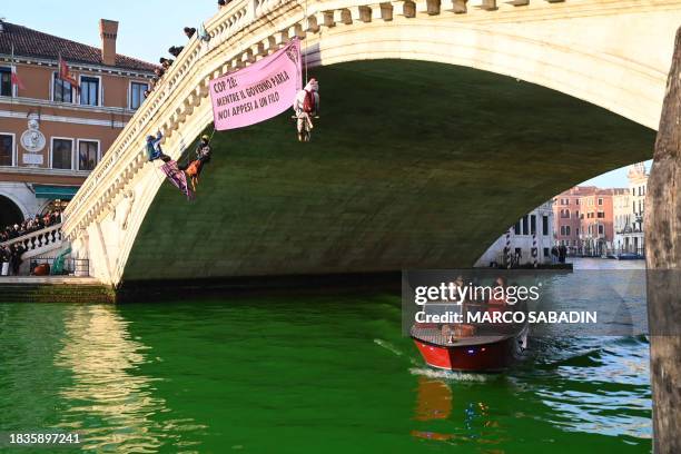 Extinction Rebellion activists are hanged on the Rialto bridge in Venice after fluorescein was poured into the Grand Canal to make the water...