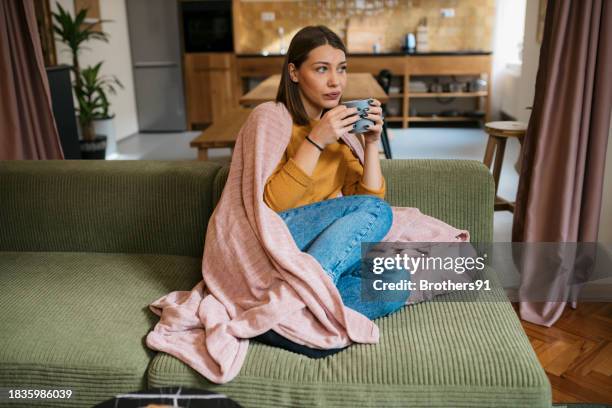femme malade buvant une boisson chaude et chaude tout en se reposant à la maison - vulnérabilité photos et images de collection